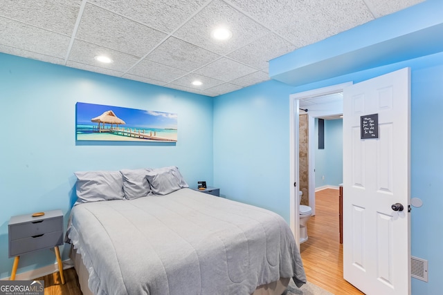 bedroom featuring hardwood / wood-style flooring and a drop ceiling