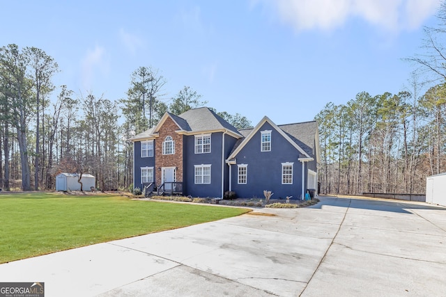 view of front of house featuring a garage, a front yard, and a storage shed