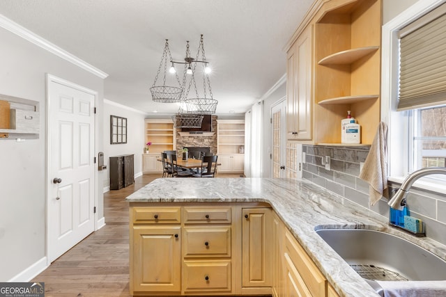 kitchen with sink, ornamental molding, light stone counters, light hardwood / wood-style floors, and light brown cabinets