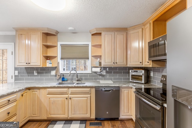 kitchen featuring light stone countertops, appliances with stainless steel finishes, sink, and light brown cabinets