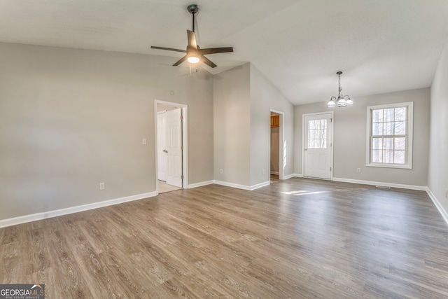 unfurnished room with lofted ceiling, hardwood / wood-style flooring, and ceiling fan with notable chandelier