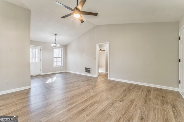 unfurnished living room with vaulted ceiling, light hardwood / wood-style floors, and ceiling fan with notable chandelier