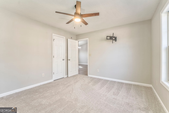 unfurnished bedroom with a textured ceiling, ceiling fan, and carpet flooring