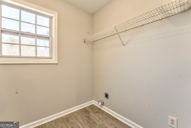 clothes washing area featuring electric dryer hookup, hardwood / wood-style floors, and a textured ceiling