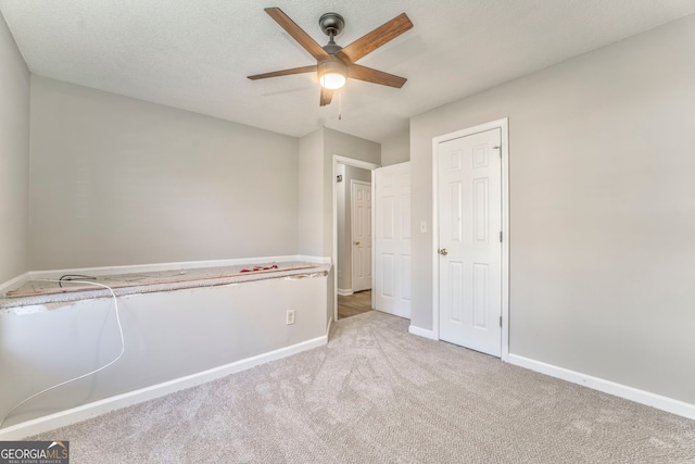 unfurnished bedroom with ceiling fan, light colored carpet, and a textured ceiling