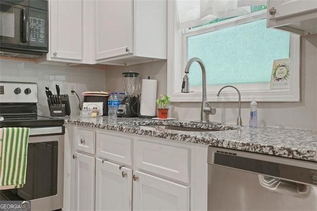 kitchen with appliances with stainless steel finishes, tasteful backsplash, white cabinetry, sink, and light stone countertops