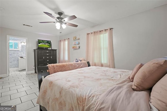 tiled bedroom featuring ensuite bathroom and ceiling fan