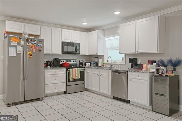 kitchen with white cabinetry, sink, light stone countertops, and appliances with stainless steel finishes