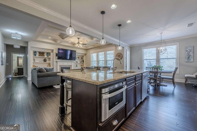 kitchen with sink, a kitchen breakfast bar, hanging light fixtures, and a center island with sink