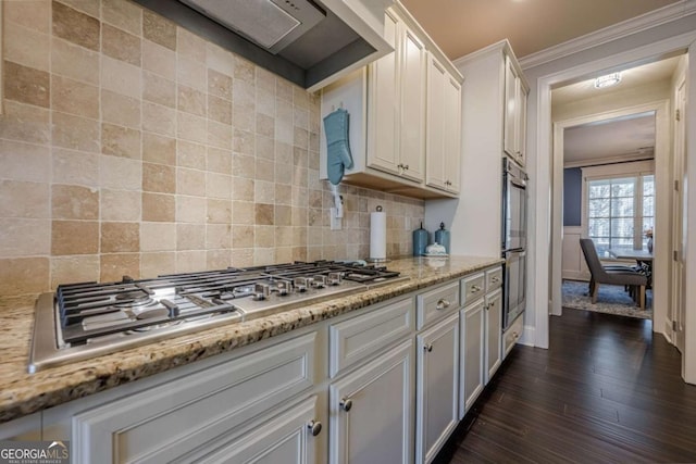 kitchen featuring tasteful backsplash, white cabinets, ornamental molding, stainless steel appliances, and light stone countertops