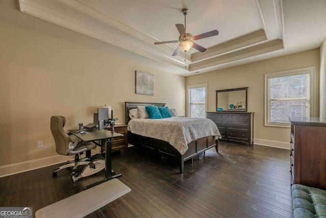 bedroom with dark hardwood / wood-style floors, ceiling fan, and a tray ceiling