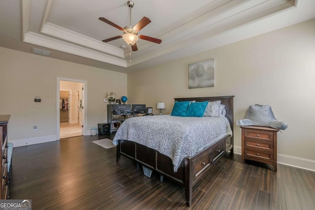 bedroom with crown molding, ceiling fan, dark hardwood / wood-style flooring, and a raised ceiling