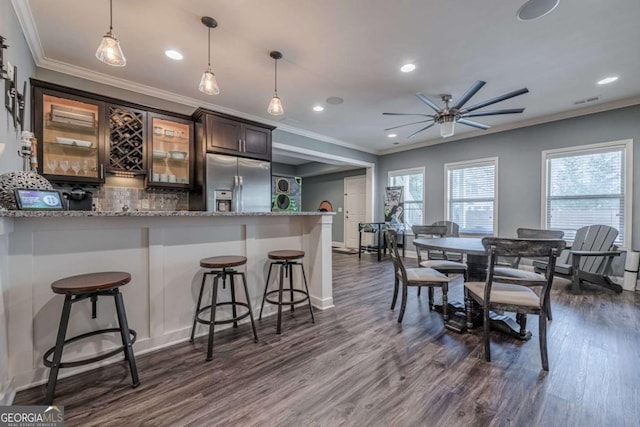 kitchen featuring pendant lighting, a kitchen breakfast bar, light stone countertops, dark hardwood / wood-style flooring, and stainless steel fridge with ice dispenser