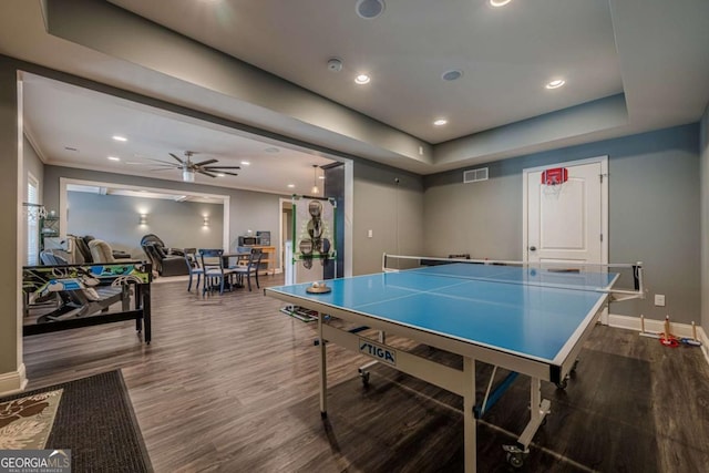 recreation room with crown molding, hardwood / wood-style flooring, a raised ceiling, and ceiling fan