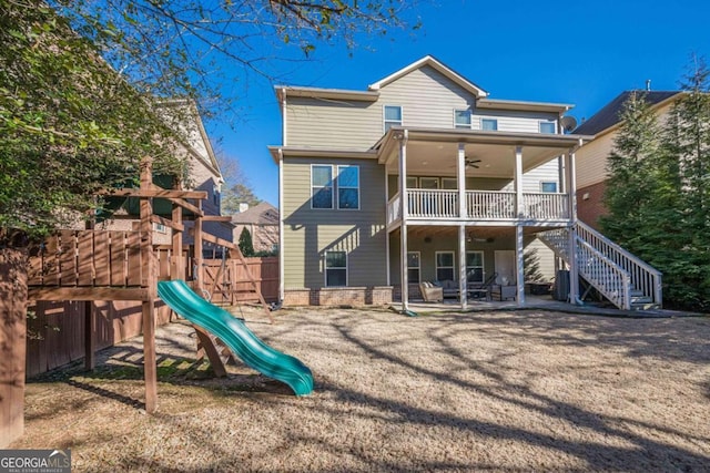 back of property featuring ceiling fan, a playground, a patio, and a lawn