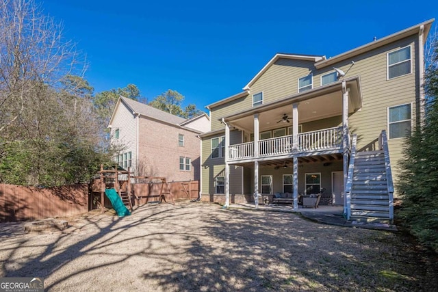 rear view of house with ceiling fan, a playground, a balcony, and a patio area