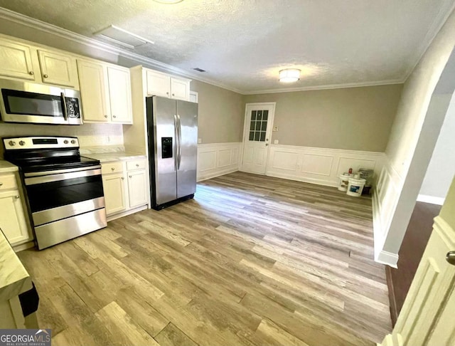 kitchen with crown molding, stainless steel appliances, and light wood-type flooring