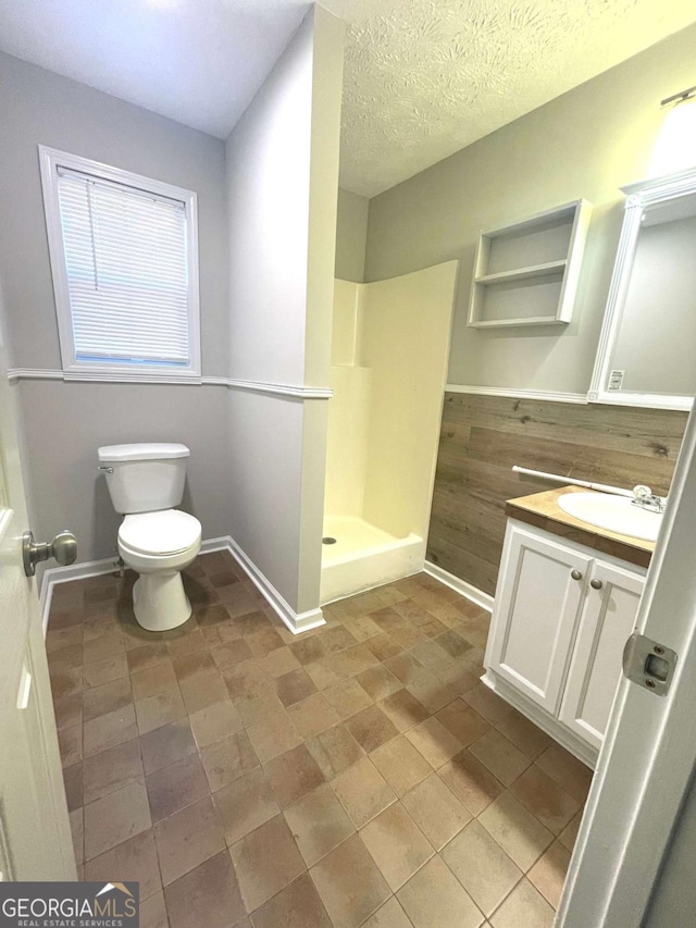 bathroom featuring a shower, vanity, a textured ceiling, and toilet