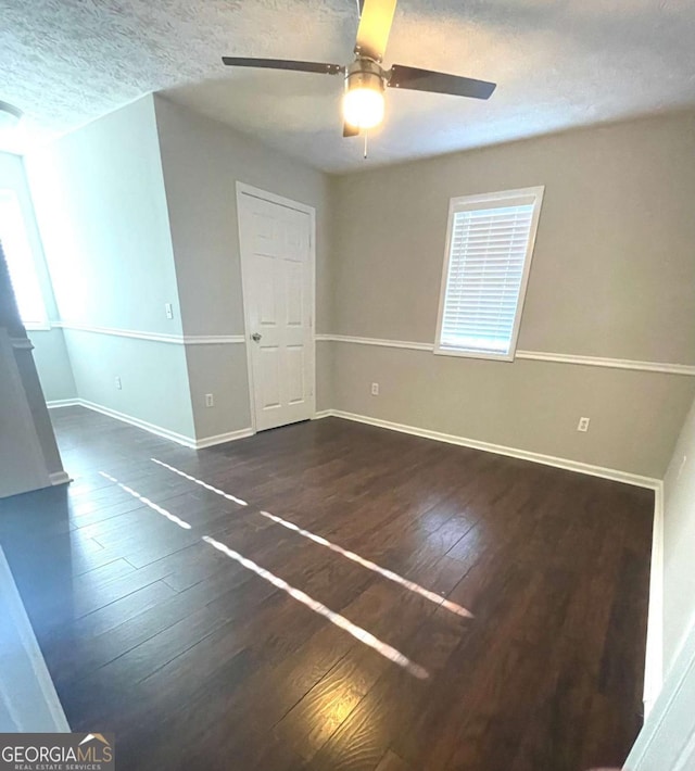 empty room with ceiling fan, dark hardwood / wood-style flooring, and a textured ceiling