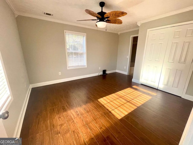 unfurnished bedroom featuring crown molding, dark hardwood / wood-style floors, ceiling fan, and a closet