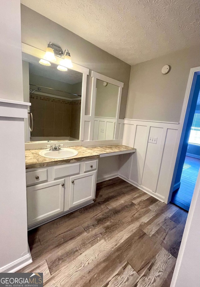 bathroom with walk in shower, vanity, hardwood / wood-style floors, and a textured ceiling