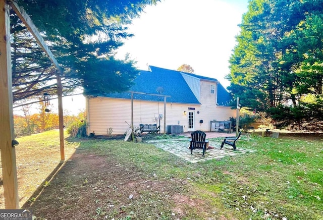 rear view of property with central AC, a patio, and a lawn