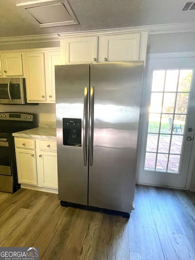 kitchen with white cabinetry, crown molding, stainless steel appliances, and light hardwood / wood-style floors