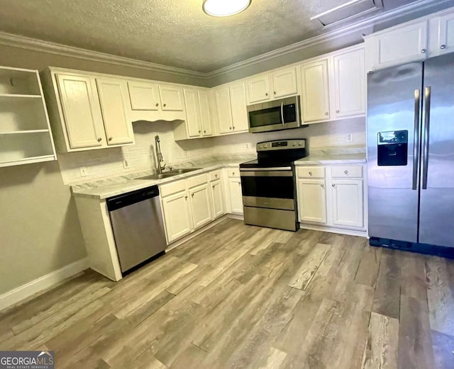 kitchen with sink, white cabinetry, stainless steel appliances, ornamental molding, and light hardwood / wood-style floors