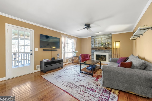 living room with crown molding, hardwood / wood-style floors, ceiling fan, and a fireplace