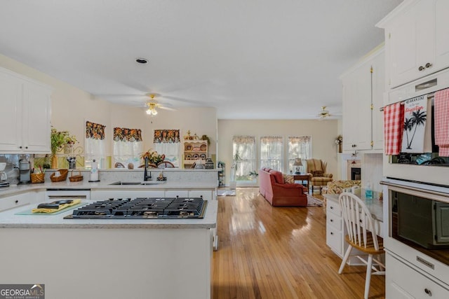 kitchen with stainless steel gas stovetop, sink, and white cabinets