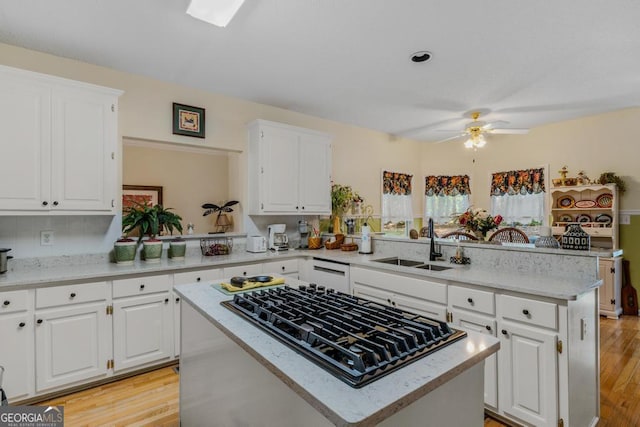 kitchen with white cabinetry, a kitchen island, stainless steel gas cooktop, and kitchen peninsula