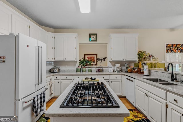 kitchen with white cabinetry, a center island, sink, and white appliances