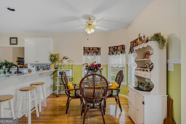 dining room featuring ceiling fan, sink, and light wood-type flooring