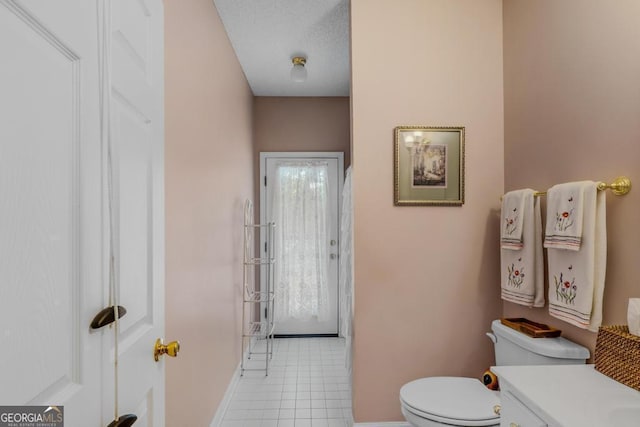 bathroom featuring vanity, toilet, tile patterned flooring, and a textured ceiling