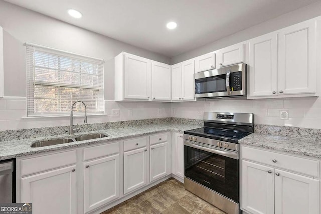 kitchen featuring stainless steel appliances, white cabinetry, sink, and backsplash