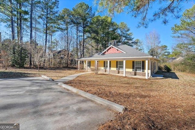 farmhouse inspired home featuring covered porch and a front yard