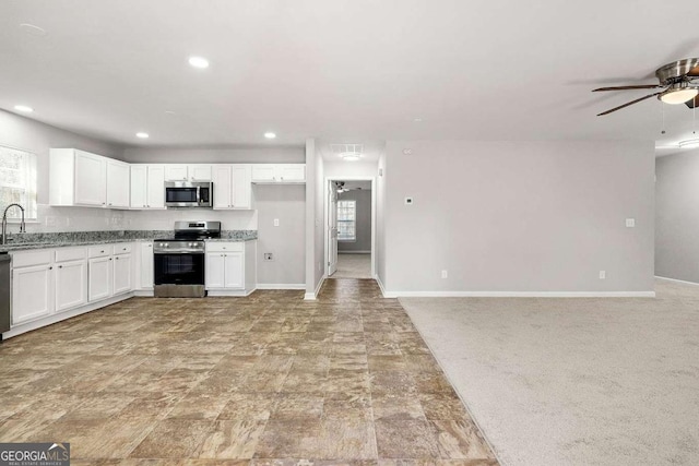 kitchen featuring appliances with stainless steel finishes, sink, white cabinets, and light stone counters