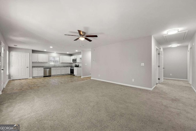 unfurnished living room with ceiling fan, sink, and light carpet