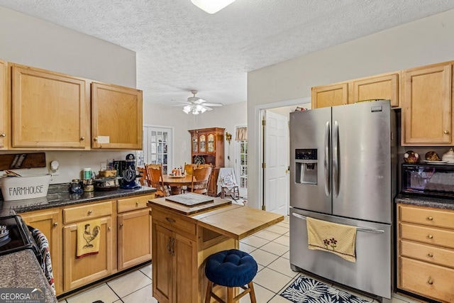 kitchen with range, a textured ceiling, light tile patterned floors, stainless steel fridge, and ceiling fan