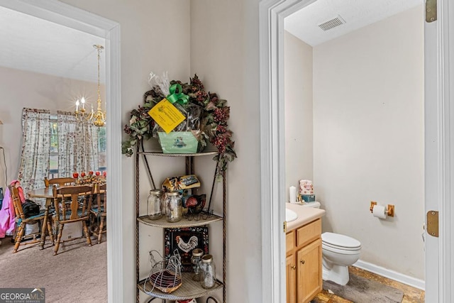 bathroom featuring vanity, toilet, and a notable chandelier