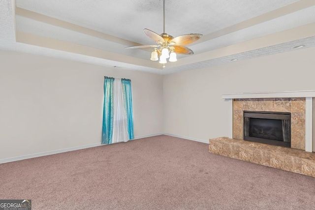 unfurnished living room featuring ceiling fan, a tray ceiling, and carpet