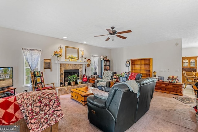 carpeted living room with ceiling fan and a fireplace