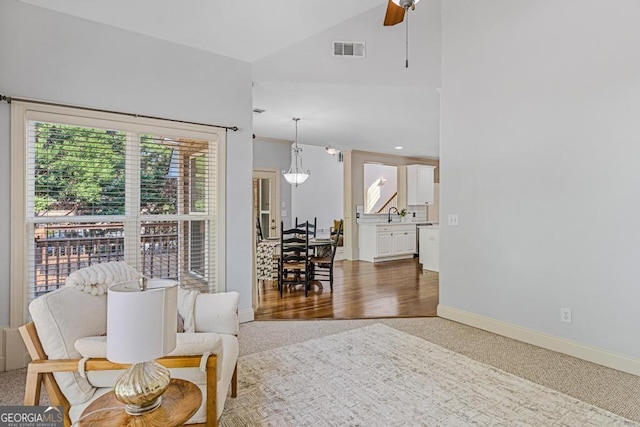 living room with ceiling fan, high vaulted ceiling, and sink