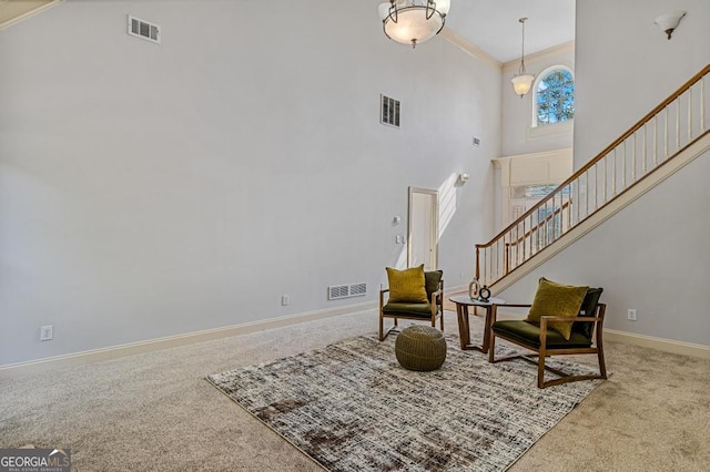 sitting room featuring a high ceiling, ornamental molding, and light carpet