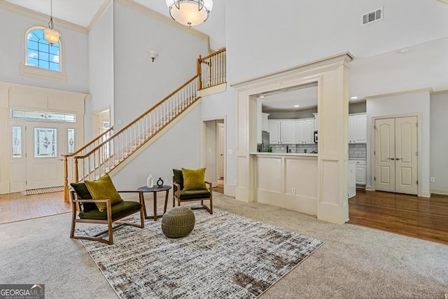 carpeted foyer with crown molding and a high ceiling