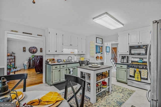 kitchen with white cabinetry, green cabinets, tasteful backsplash, and appliances with stainless steel finishes