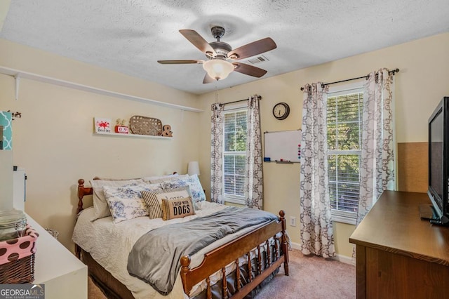 carpeted bedroom featuring ceiling fan and a textured ceiling