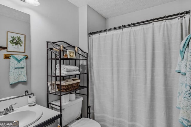 bathroom featuring vanity, a shower with curtain, toilet, and a textured ceiling