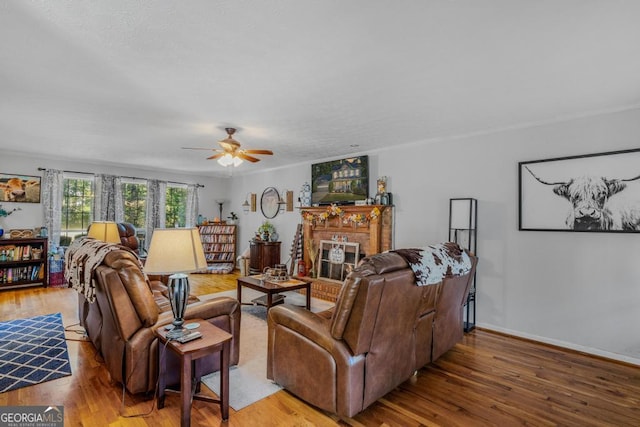 living room with a brick fireplace, hardwood / wood-style floors, and ceiling fan