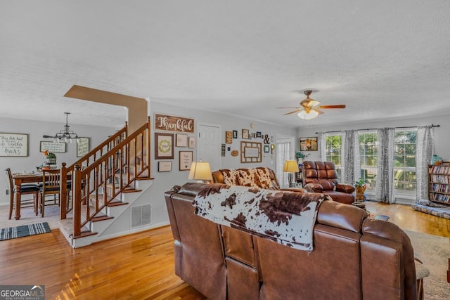 living room with ceiling fan, a textured ceiling, and light wood-type flooring